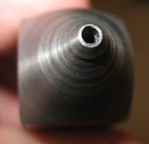 The refinished nozzle tip. Note that the outer rim of the tip is now round, assuring leak-free operation. However, the hole is out of round and shows a ridge inside it. which may cause turbulent flow of the metal jet.