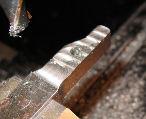 Uneven milled surface. The wide smooth area farthest from the end was caused when the endmill took a slightly heavier bite and the vibration and downward pull (from the spiral shape of the cutter) draw the milling head down to the lower limit of its backlash. The other stripes are due to the mill being out of tram a bit.