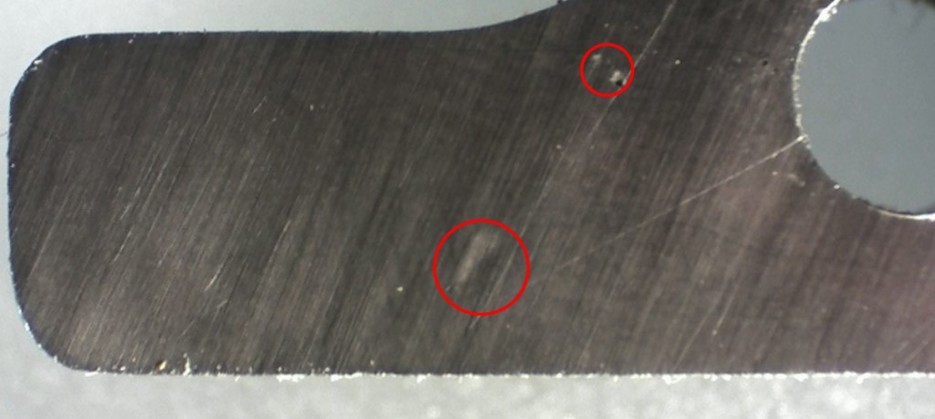 The larger circle shows the gentle dent left by the fleck of type metal. The smaller circle shows two sharper-edged dents from other unknown dirt.